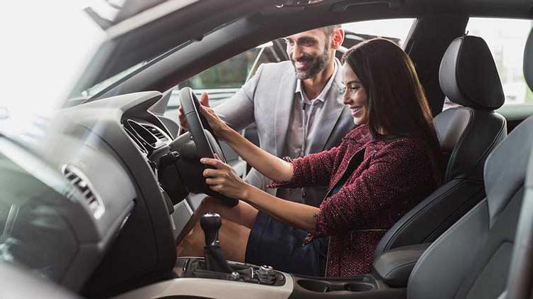 With his daughter behind the wheel of a parked car, a dad offers instruction.